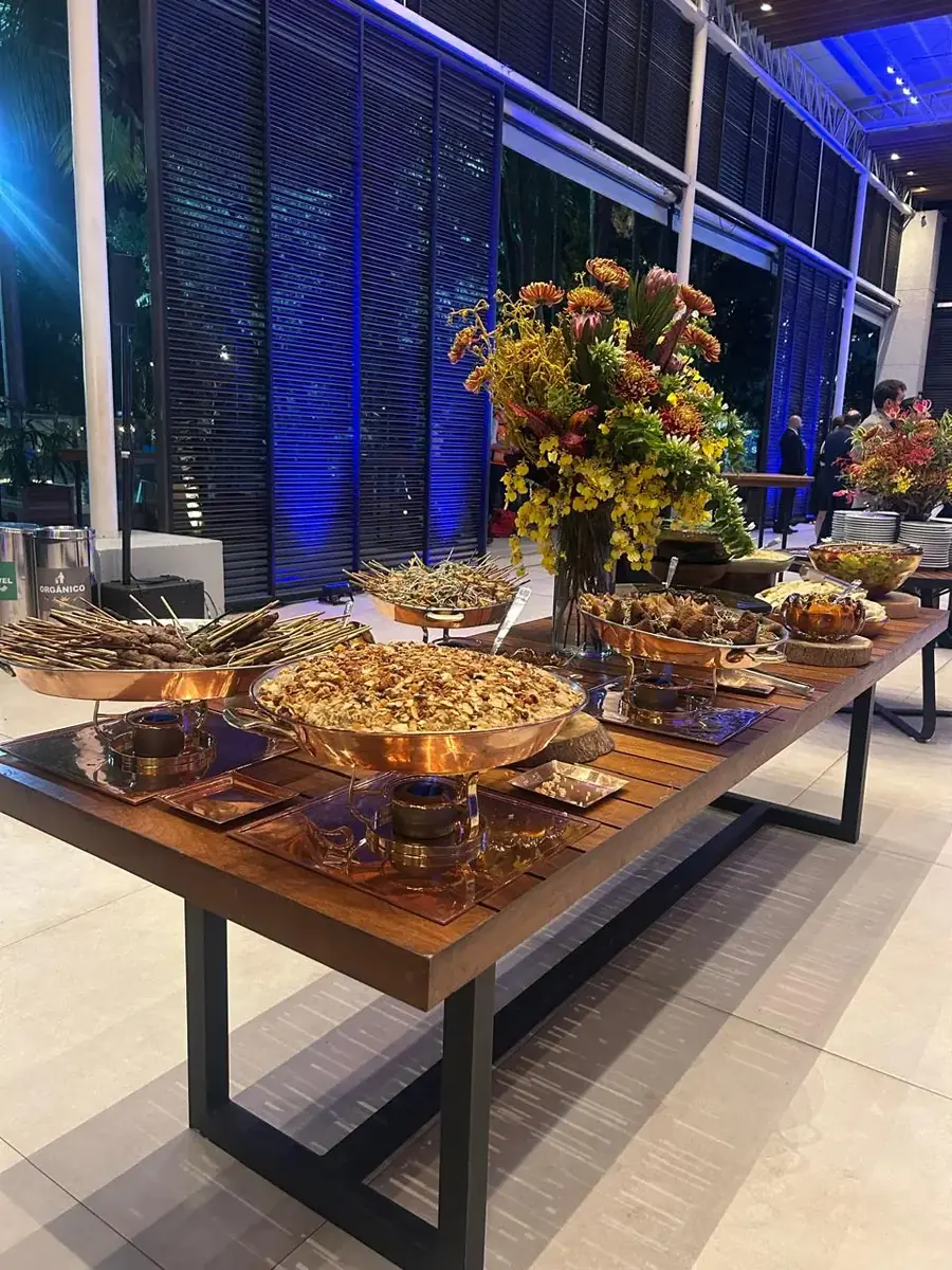 Mesa de buffet montada à noite, com arranjo floral e travessas de prata