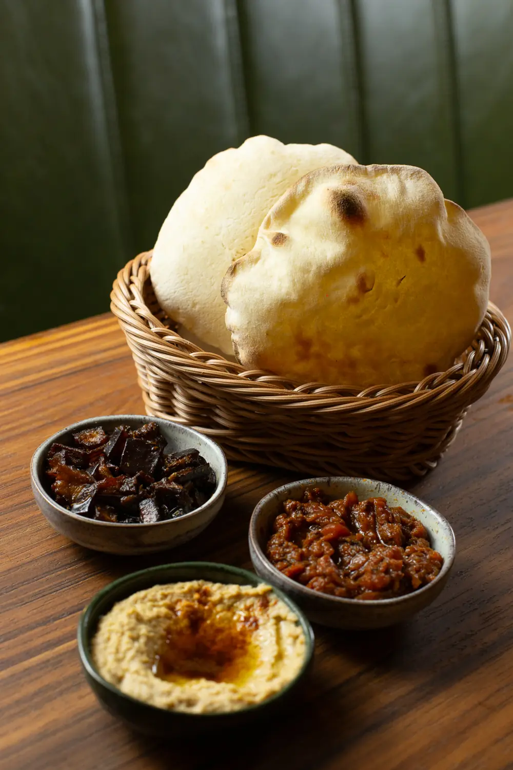 Pães pita numa cesta com homus, matbucha e antepasto de berinjela